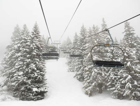 empty ski lift in mist between snow covered treesの写真素材
