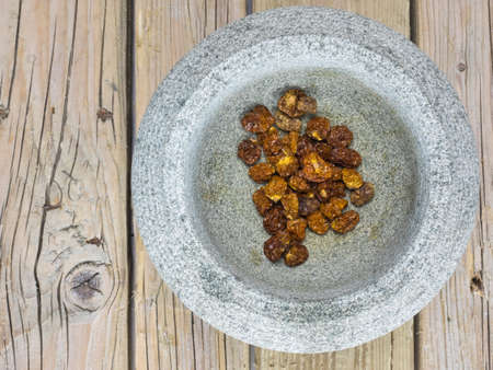 dried inca berries in a rustic stone bowl with an old wooden table top behindの写真素材