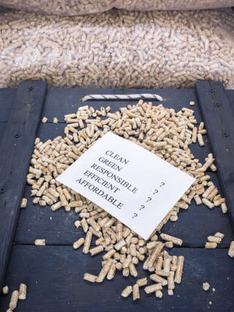wood pellets in a wood pellet store with a check list carrying the words clean, green, responsible, efficient and affordable with question marks against each-concept questioning environmental benefit of wood pellet fuelsの写真素材