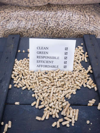 wood pellets in a wood pellet store with a check list carrying the words clean, green, responsible, efficient and affordable checked offの写真素材