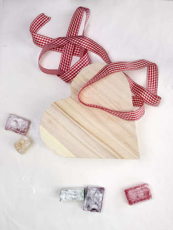 colourful turkish delight  with a rustic wooden heart shaped presentation box and gingham ribbon with white surface behindの写真素材