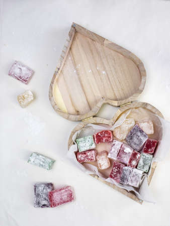 colourful turkish delight in a rustic wooden heart shaped presentation box with white surface behind