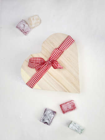colourful turkish delight  with a rustic wooden heart shaped presentation box tied with a red and white  ribbon with white surface behindの写真素材