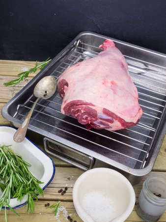 raw leg of lamb on roasting tin with salt pepper and fresh rosmaryの写真素材