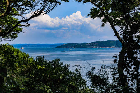 The park and lighthouse of Kannonzaki as seen through the trees of Sarushima, a small natural island on Tokyo Bay.の写真素材