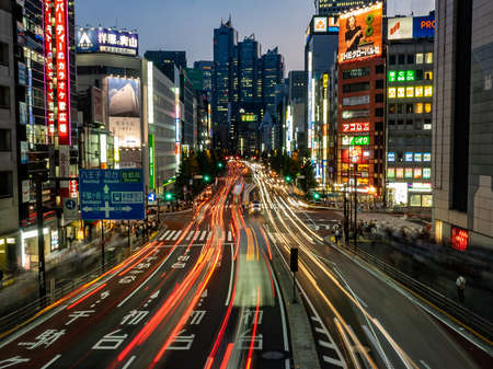 The streets of Shinjuku, Tokyo at night, as seen from a pedestrian foot bridge, The light streaks from the long exposure show the business of the huge city.のeditorial素材