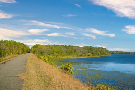 Early Autumn landscape of the Paul Bunyan Trail passing by a peaceful blue lake on a sunny day near Bemidji, Minnesota, USA.の写真素材