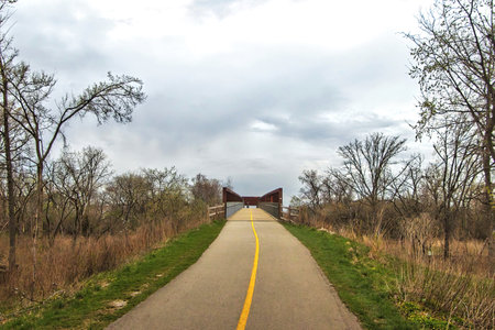 The North Branch Trail climbs to a distant bridge beneath a cloudy sky on a Spring day near Chicago, Illinois.の写真素材
