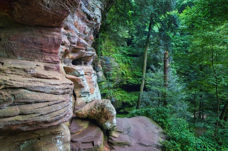 Cloudy summer landscape of a trail passing between rock cliffs and lush green trees at Hocking Hills State Park in Hocking County, Ohio.の写真素材