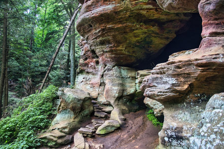 Cloudy summer day landscape of a trail between layered rock cliffs and lush green trees at Hocking Hills State Park in Hocking County, Ohio.の写真素材