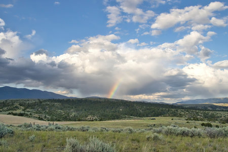 Landscape of a rainbow above distant mountains an overcast Summer evening near Townsend,  Montana.の写真素材