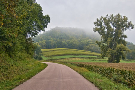 Autumn landscape of a road curving past fields and through rolling hills in Wisconsinâs Driftless Area near Trempealeau, Wisconsin.の写真素材