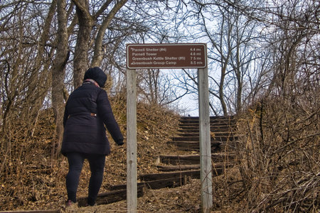 Parnell, Wisconsin, USA â€“ February 24, 2026: View of a female hiker ascending steps and...