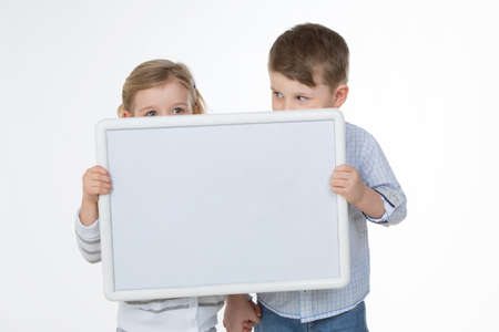 two children hiding their faces behind empty billboardの写真素材