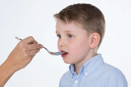 someone gives medicine to a sick kidの写真素材