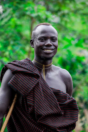 Omo River Valley, Ethiopia - November 29, 2020: Portrait of Happy and Satisfied African Man with Traditional dress in the local Mursi tribe villageのeditorial素材