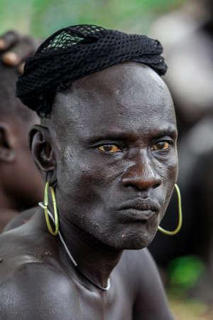Omo River Valley, Ethiopia - November 29, 2020: Close up Portrait of  African Man with Golden...