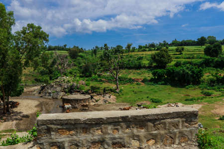 Breathtaking View to the Traditional African Houses, Green Trees and Mountains under Cloudy Blue Sky of the Omo River Valley, Ethiopiaの写真素材