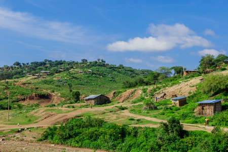 Breathtaking View to the Traditional African Houses, Green Trees and Mountains under Cloudy Blue Sky of the Omo River Valley, Ethiopiaの写真素材