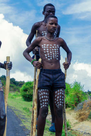 Omo River Valley, Ethiopian -November 2020: Close up portraits of Benna Tribe Young Boys with Traditional Body Painting on the Long Wooden Sticksのeditorial素材