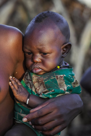 Omo River Valley, Ethiopian -November 30, 2020: Dassanech Tribe Woman in Traditional Bright Necklace with Little and Cute Infant on Hands in the Local Villageのeditorial素材