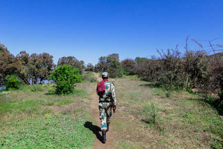 Gondar, Ethiopia - December 01, 2020: Escort Man with the Gun posing with the Green Valley of Simien Mountainsのeditorial素材