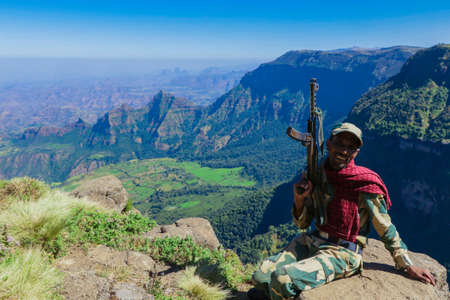 Gondar, Ethiopia - December 01, 2020: Escort Man with the Gun posing with the Green Valley of Simien Mountainsのeditorial素材