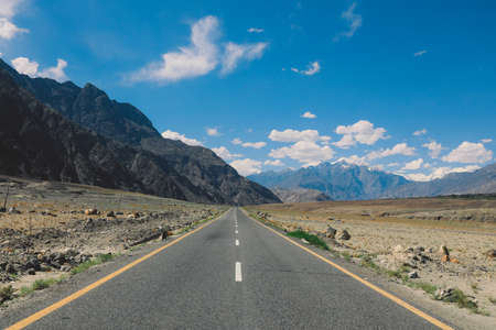 Asphalt Road in the High Gilgit Baltistan Mountains under the Blue Clouds, Pakistanの写真素材
