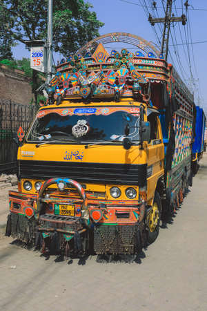 Lahore, Pakistan - July 08, 2021: Bright and Colorful Yellow Pakistani Truck with traditional Decorations and Design on the Lahore Streetのeditorial素材