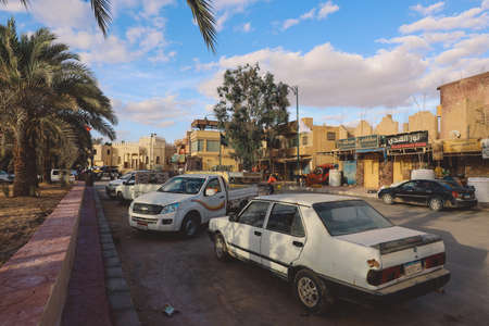 Siwa, Egypt - November 03, 2021: Cityscape View with Old Cars, Local People and Buildings in the...