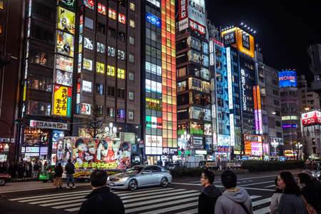 Tokyo, Japan - January 08, 2020: Tourists and Local People walking on the Beautiful Tokyo street among passing Cars in the Night time