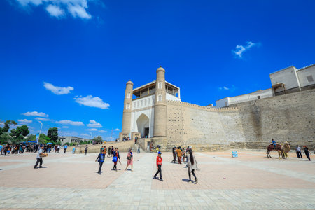 Bukhara, Uzbekistan - May 05, 2022: View to the Tourists near the Entrance Gates of the Ark, the Medieval massive Bukhara Fortress in Uzbekistanのeditorial素材