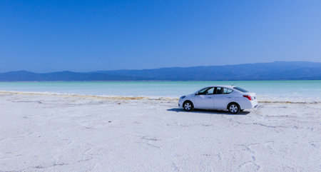 Lake Assal, Djibouti - November 08, 2022: Man Tourist on the White Car on the Salty Surface of the Lakeのeditorial素材