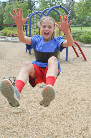 Smiling, happy teen girl hanging on moving swingの写真素材