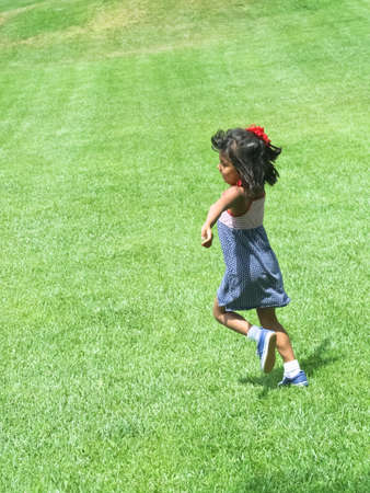 happy young hispanic girl running in parkの写真素材
