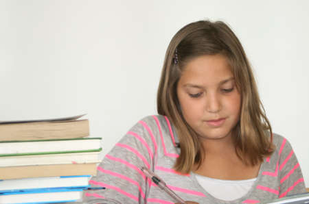 3 	Pretty preteen student studying with book stackの写真素材