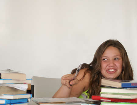 Pretty giggling teen student pointing at tall book stackの写真素材