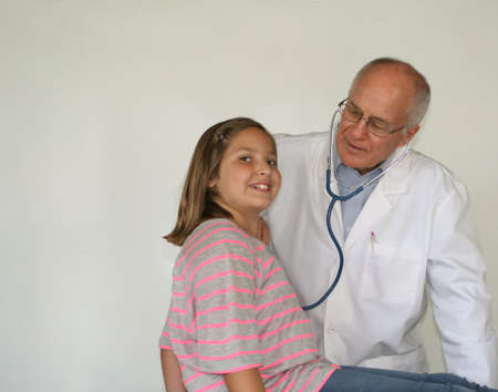Older male doctor with pretty preteen female patientの写真素材
