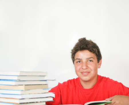 Happy teenage boy studying books with book stackの写真素材