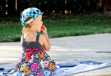 female toddler eating watermelon near swimming poolの写真素材