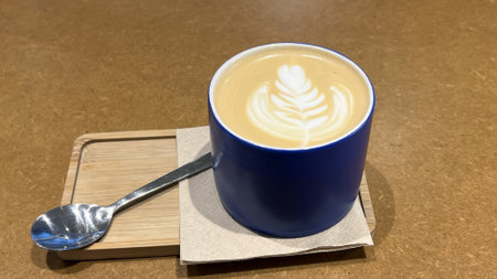 A cup of cappuccino with latte art on brown background