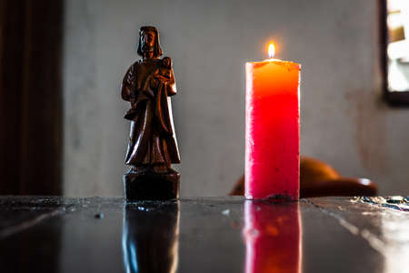 saint joseph and a colored burning candle on top of a tableの写真素材
