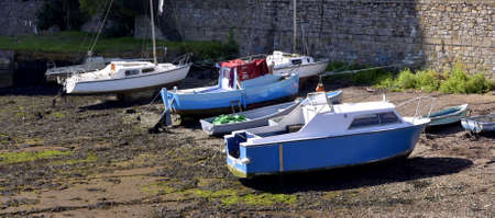 Blue and White Fishing boats moored at low tide in the Cornish harbour England UK