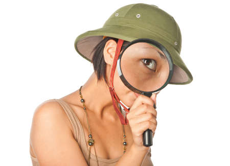 Girl in a pith helmet looks throught magnifierの写真素材