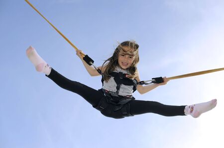 Young girl playing on bungee trampolineの写真素材
