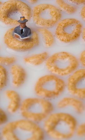 A small man reading a book while floating in cerealの写真素材