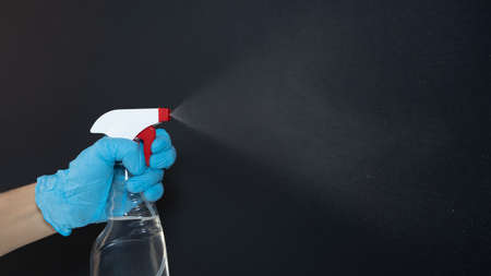 A hand with medical glove holds a bottle spray with a cleaning or disinfecting agent.の写真素材
