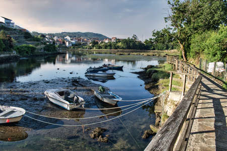Small recreational and fishing boats beached and moored at low tide in Ponte Sampaio, Pontevedra...