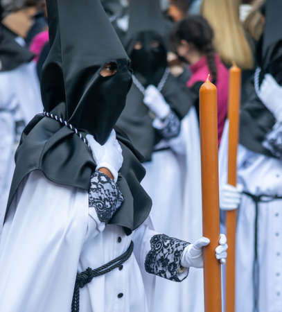 Holy Week Valladolid, brotherhood of the holy Christ of Medinacelli with large candle and black hoodの写真素材