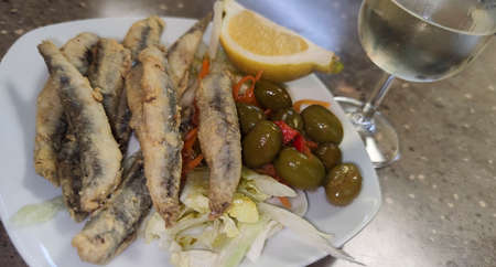 Tapa in Granada of breaded and fried fish with olives and very cold white wineの写真素材
